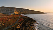 Aerial view of a beautiful sunrise over the ocean and rugged coastline with cliffs, Arico, Spain.