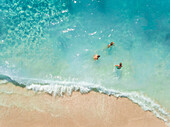 NIKITAS, GREECE - 13 JULY 2018: Aerial view of kids playing in the waves on sandy beach in turquoise sea.