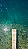 Aerial view of a person jumping from a pontoon in the sea.