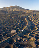 Aerial view of a woman walking among volcano holes formation at Timanfaya national park, Lanzarote Island, Canary Islands, Spain.