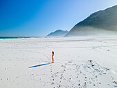 Aerial view of woman in white swimsuit on white beach, Cape Town, South Africa.