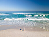 Aerial view of woman standing on beach in front of waves, Cape Town, South Africa.