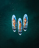 Aerial view of a female surfer paddling on a blue ocean with a surfboard, Primorje-Gorski Kotar, Croatia.