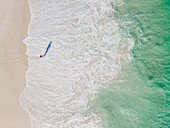 Aerial view of woman standing on beach in front of waves, Cape Town, South Africa.
