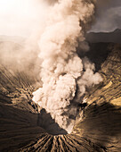 Aerial view of the majestic Bromo volcano with smoke and ash rising from its crater, Sukapura, East Java, Indonesia.