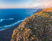 Aerial view of a person standing on the rocks on mountain top at Arco Famara, Lanzarote, Canary Islands, Spain.