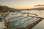 Aerial view of Cannonvale city port and harbour with breakwater structure facing the Pioneer Bay at sunset, Queensland, Australia.