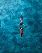Aerial view of women snorkeling in the clear turquoise waters of a tropical island, Croatia.