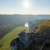 Aerial view of a woman standing on the rocks with Walzin castle in background at sunset, Dinant, Namur, Belgium.