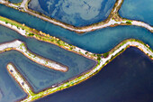 Aerial view of the patterns and colors of salt evaporation ponds during sunrise time in Aveiro, Portugal