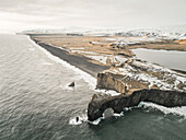 Aerial view of Dyrhólaey peninsula with the black arch of lava standing in the sea in Iceland.