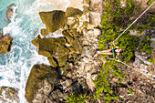 Aerial view of attractive woman swinging at Diamond Beach shore, Indonesia.