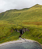 Aerial view of a waterfall along the coast, Driftwood Bay, Unalaska island, Alaska, United States.