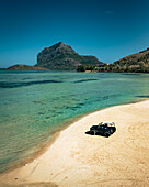Aerial view of an off road car parked along the shoreline on the beach with Le Morne Brabant mountain in background, Riviere Noire, Mauritius.
