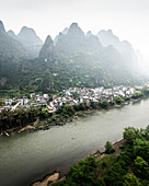Aerial view of picturesque karst mountains and a tranquil river winding through a lush village, Guilin, China.
