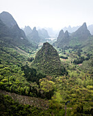 Aerial view of majestic karst mountains and lush greenery in a tranquil valley, Guilin, China.