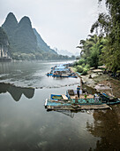 Aerial view of serene karst mountains and a tranquil river with boats, Guilin, China.
