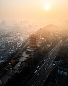 Aerial view of beautiful Yellow Crane Tower amidst a vibrant cityscape at sunset, Wuhan, China.