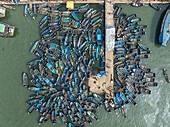 Aerial view of busy traditional dock with colorful wooden boats and vibrant waterway activity, Yam Zone, Port Harcourt, Rivers State, Nigeria.
