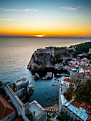 Aerial view of the historic fortress and old town at sunset with vibrant colors over the Adriatic Sea, Dubrovnik, Croatia.