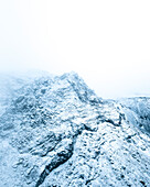 Luftaufnahme des mit Schnee und Eis bedeckten Gipfels der Blauen Berge an einem nebligen Wintertag, Kopavogur, Island.