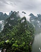 Aerial view of majestic karst mountains and a serene river shrouded in fog, Guilin, China.
