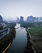 Aerial view of picturesque karst mountains and serene river flowing through lush countryside fields and tranquil village, Guilin, China.
