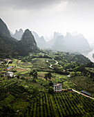 Aerial view of serene and picturesque karst mountains and lush valleys with farmland and homes, Guilin, China.