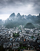 Aerial view of picturesque karst mountains and urban landscape with buildings and rooftops, Guilin, China.