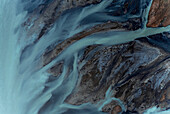 Aerial view of beautiful blue patterns, and swans swimming in the water of glacial river Héraosvotn in North Iceland.