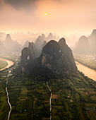 Aerial view of serene karst mountains and a winding river at sunset, Guilin, China.