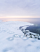 Aerial view of a man walking his dog on the frozen sea in Muraste, Estonia.