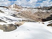 Aerial view of majestic snowy mountains with porters in Deosai National Park, Skardu, Pakistan.