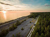 Aerial view of a car driving on a path close to the sea at sunset on Island Vormsi.