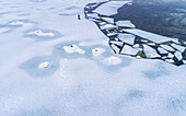 Aerial view of a man walking his dog on the frozen sea in Muraste, Estonia.