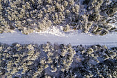 Aerial view of a road covered with snow in the forest of Naage in Estonia.