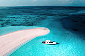 Aerial view of people with a motor boat on a sandbank along the shoreline with white sand beach, South Ari Atoll, Maldives.
