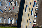 Aerial view of parked semi trucks and cars underneath a freeway at a parking lot in Romeoville, IL - USA