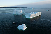 Aerial drone view a huge iceberg with an arch surrounded by a red boat, Ilulissat, Greenland, Arctic.