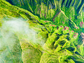 Luftaufnahme von üppig grünen Bergen und Tälern mit zerklüfteten Felsen und Wolken, Kauai, Na Pali Coast, Vereinigte Staaten