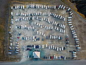 Aerial view of a crowded parking lot filled with recreational vehicles and cars in a scenic landscape, Nordkapp, Norway.