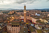 Luftaufnahme des Torre del Mangia mit der Stadtsilhouette bei Sonnenuntergang, einer berühmten Sehenswürdigkeit auf der Piazza del Campo, Siena, Toskana, Italien.