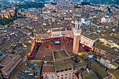 Luftaufnahme des Torre del Mangia mit der Stadtsilhouette bei Sonnenuntergang, einer berühmten Sehenswürdigkeit auf der Piazza del Campo, Siena, Toskana, Italien.