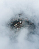 Luftaufnahme von Trentinara, einer kleinen Stadt auf einem Berggipfel mit niedrigen Wolken und dichtem Nebel Salerno, Kampanien, Italien.