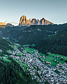 Luftaufnahme von St. Ulrich, einem kleinen Dorf in den Dolomiten, bei Sonnenuntergang, Trentino, Südtirol in Norditalien