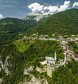 Luftaufnahme der Kirche San Martino in Valle di Cadore, einer kleinen Stadt inmitten von Bergen und dem Berg Antelao im Hintergrund in den Dolomiten in Venetien, Belluno, Italien.