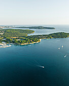 Aerial view of a motorboat sailing along the Adriatic Sea coastline near Pula at sunset, Istria, Croatia.