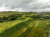 Luftaufnahme von üppig bewachsenen Hügeln und Grünflächen unter einem bewölkten Himmel, Lochgilphead, Vereinigtes Königreich.