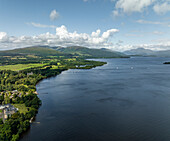 Aerial view of serene Loch Lomond surrounded by majestic mountains and lush greenery, Alexandria, United Kingdom.