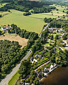 Aerial view of beautiful Loch Lomond surrounded by lush greenery and tranquil village, Trossachs National Park, Scotland.